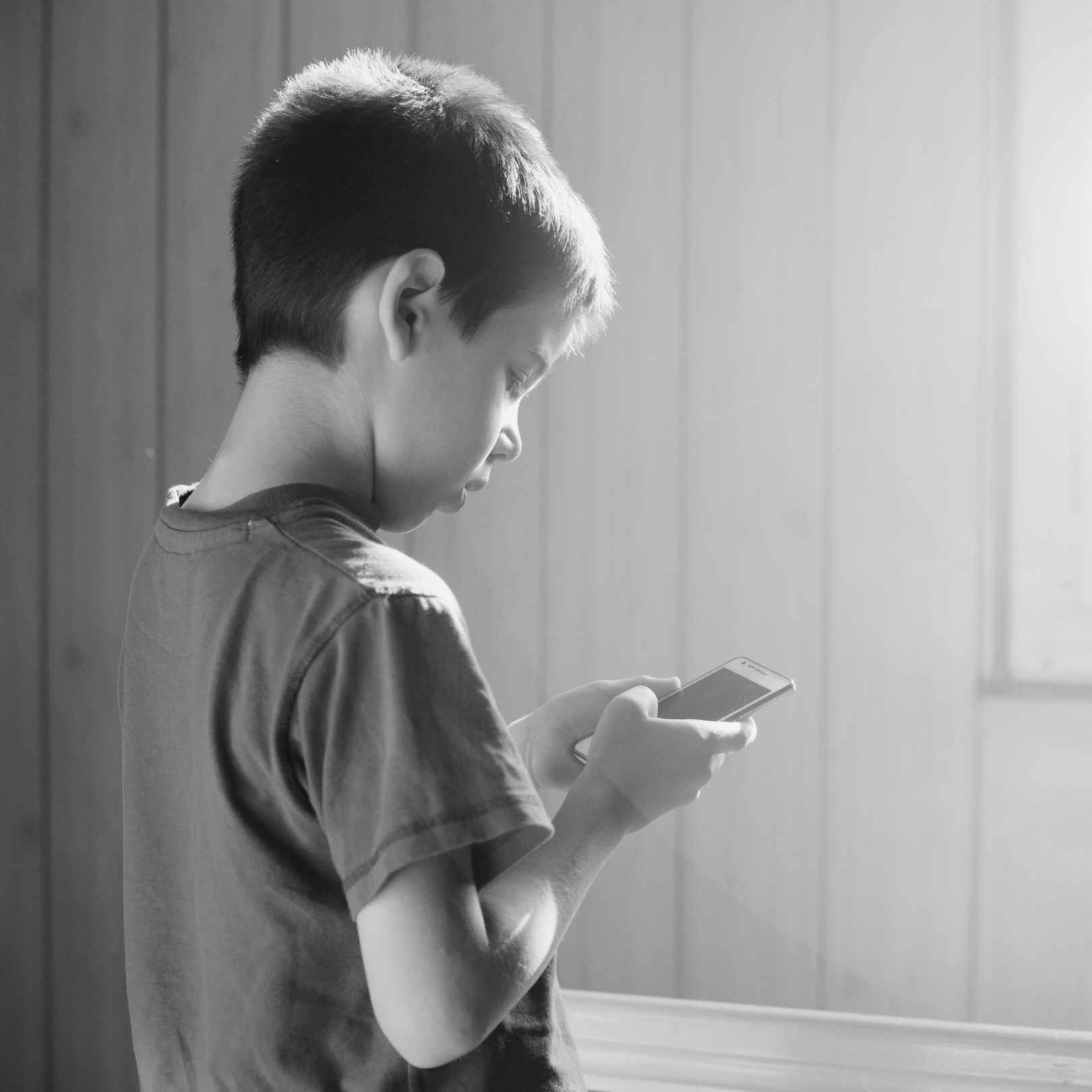 Black and white photo of a child looking at a smartphone.